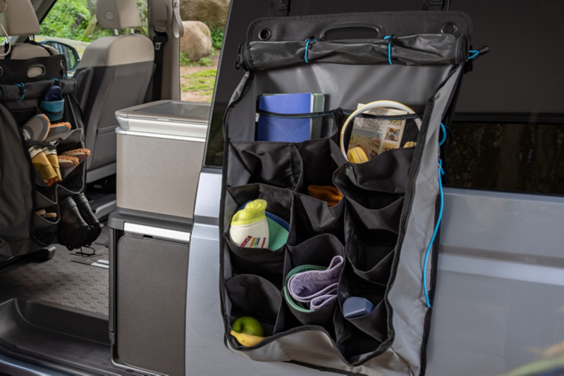 In der geöffneten Schiebetür des VW California COAST hängt eine praktische Tasche für ausreichenden Stauraum.