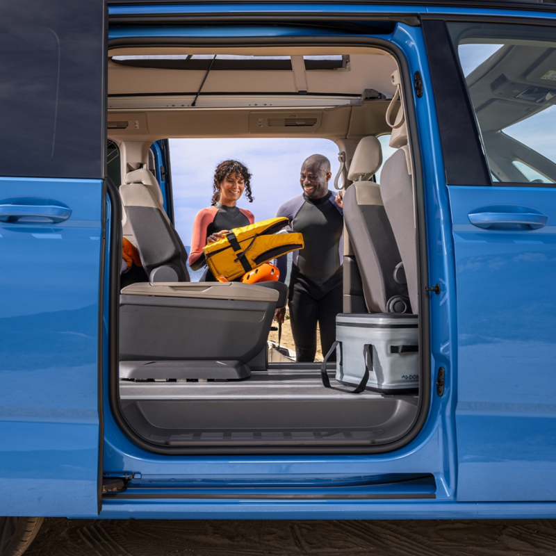 Furgoneta camper Volkswagen puertas abiertas y dos personas sacando material de buceo