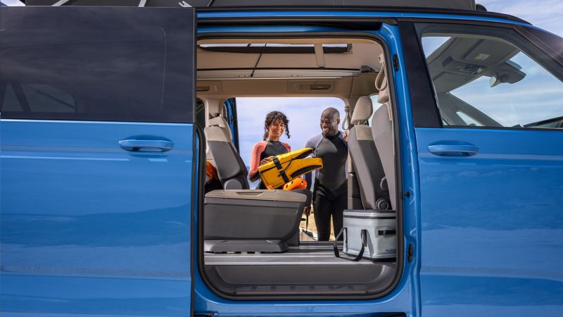 Ein Pärchen in Neoprenanzug laden ihre Taucherausrüstung aus einem VW California.