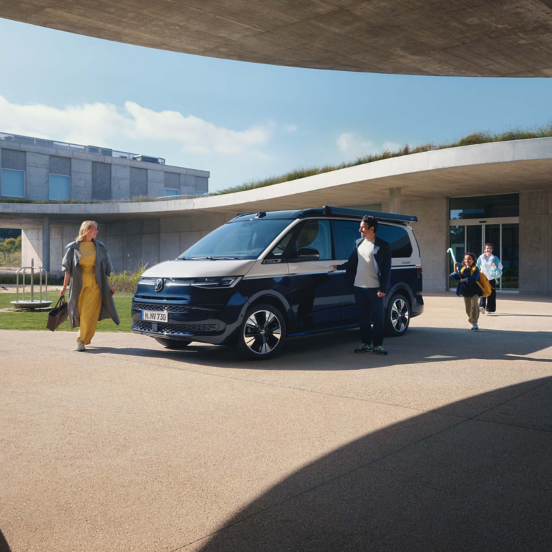 Eine Familie steig in einen VW California ein.