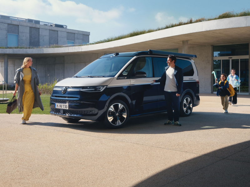 Eine Familie steig in einen VW California ein.