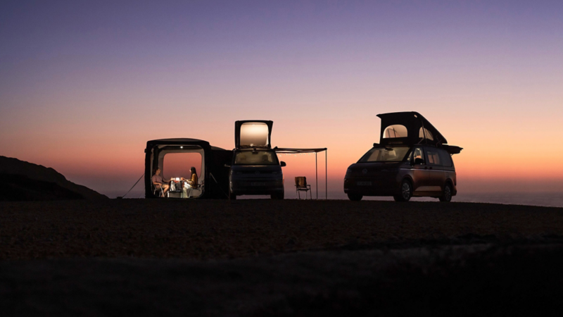 Dwa Volkswageny California na plaży podczas zachodu słońca.