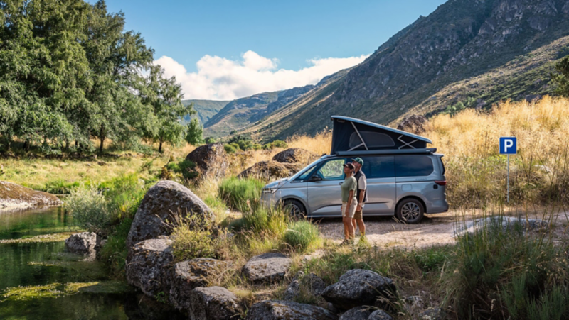 Un van VW California au bord d’une rivière.