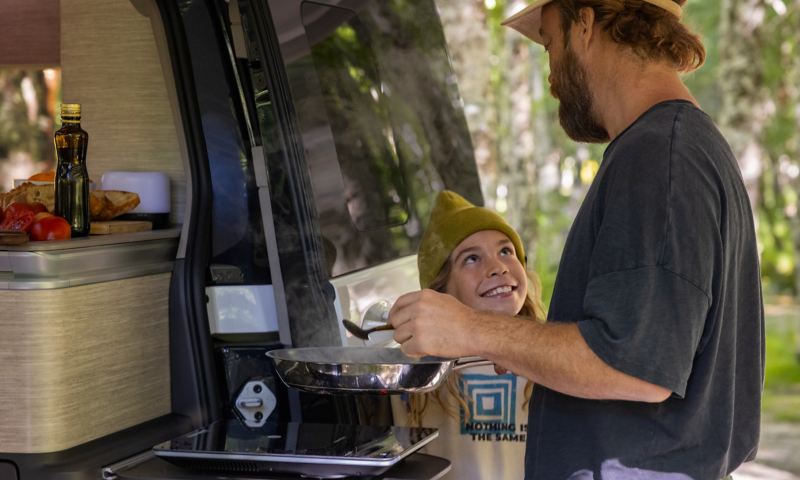 Un uomo e un bambino in piedi davanti alla cucina del Volkswagen California.