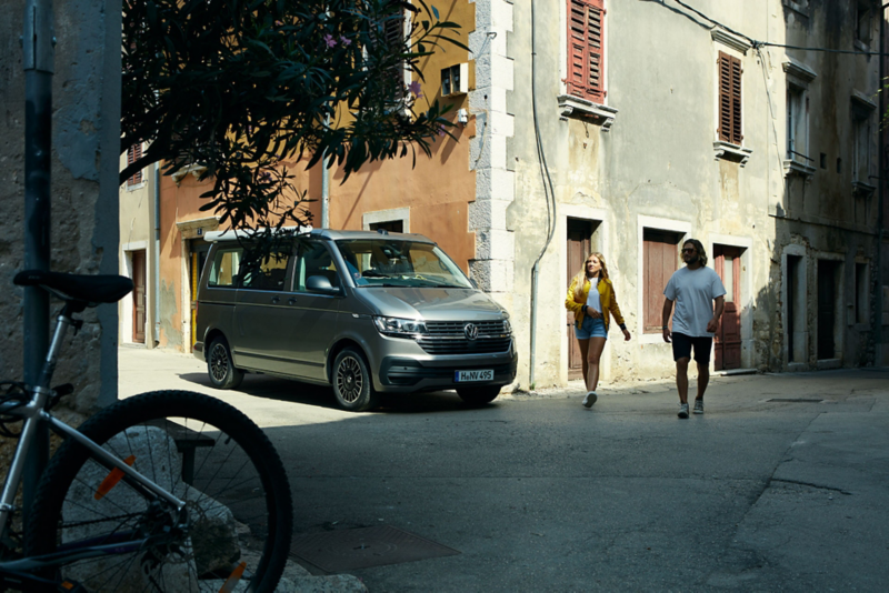 California 6.1 VW dans une ville au soleil avec un couple