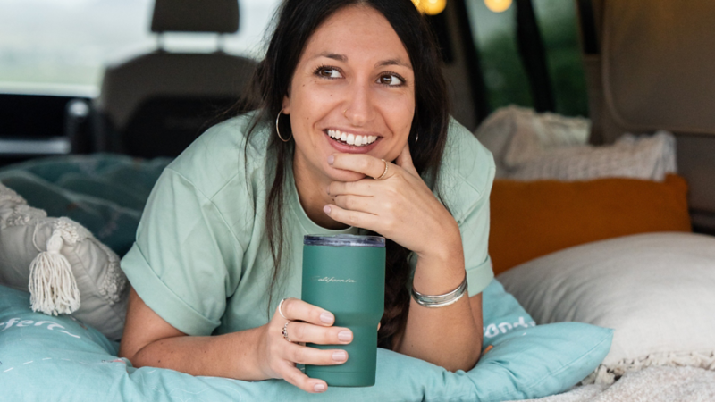 Frau mit Becher im Innenraum eines Campers