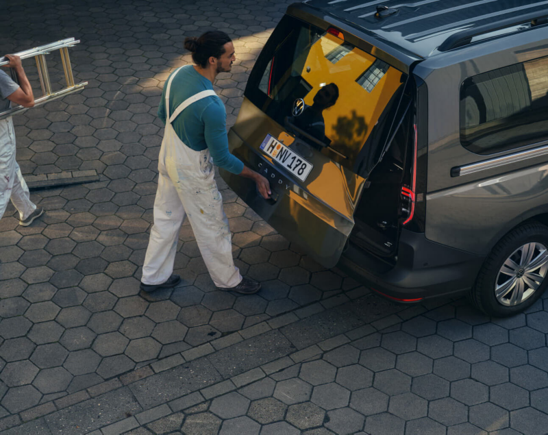 Un homme charge quelque chose dans le coffre d’un Volkswagen Caddy Cargo Double Cab