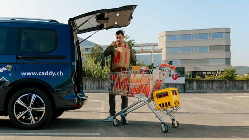 Ein Man belädt einen Caddy mit Einkäufen