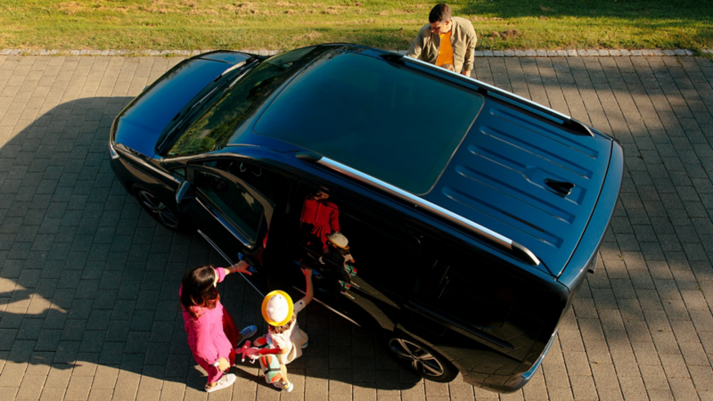 Une famille monte dans le Caddy, le tout est visible depuis une vue d'ensemble.