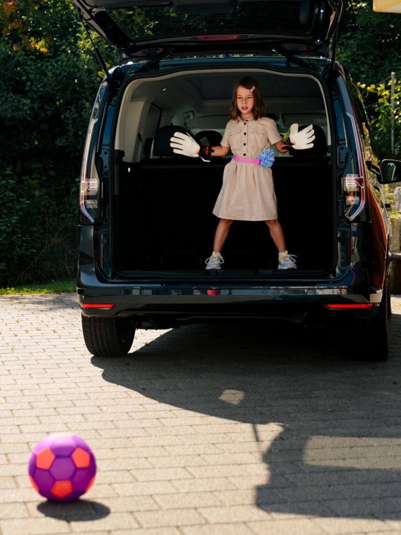 Zwei Kinder spielen Fussball und benutzen den Kofferraum vom Caddy als Tor
