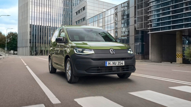 Caddy fährt durch eine Straße zwischen modernen Bürogebäuden. 