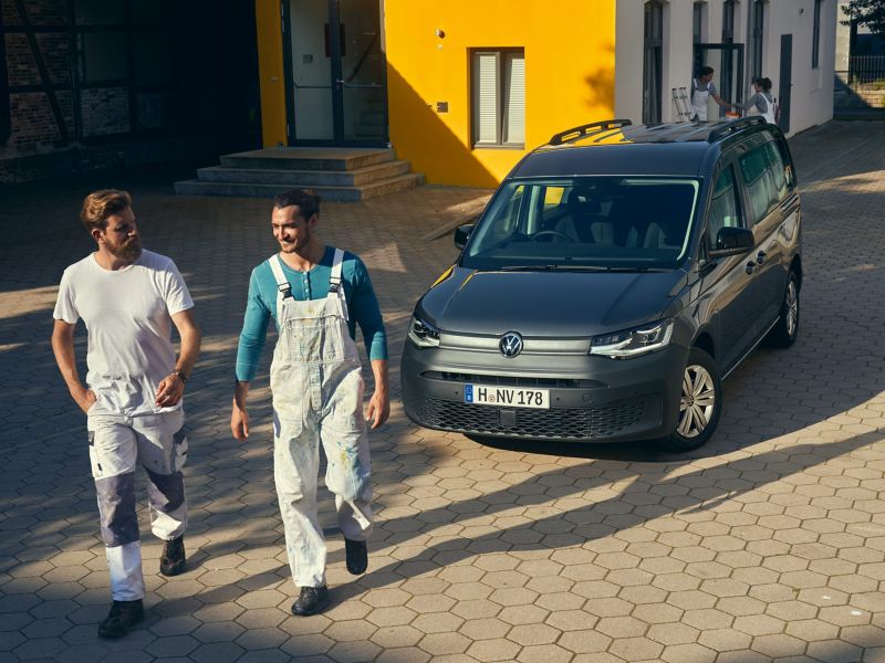 Two tradesmen walking away from parked Volkswagen Caddy Cargo Crewvan.