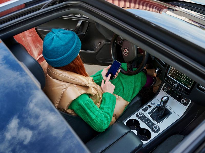 A woman holding a phone in a convertible car