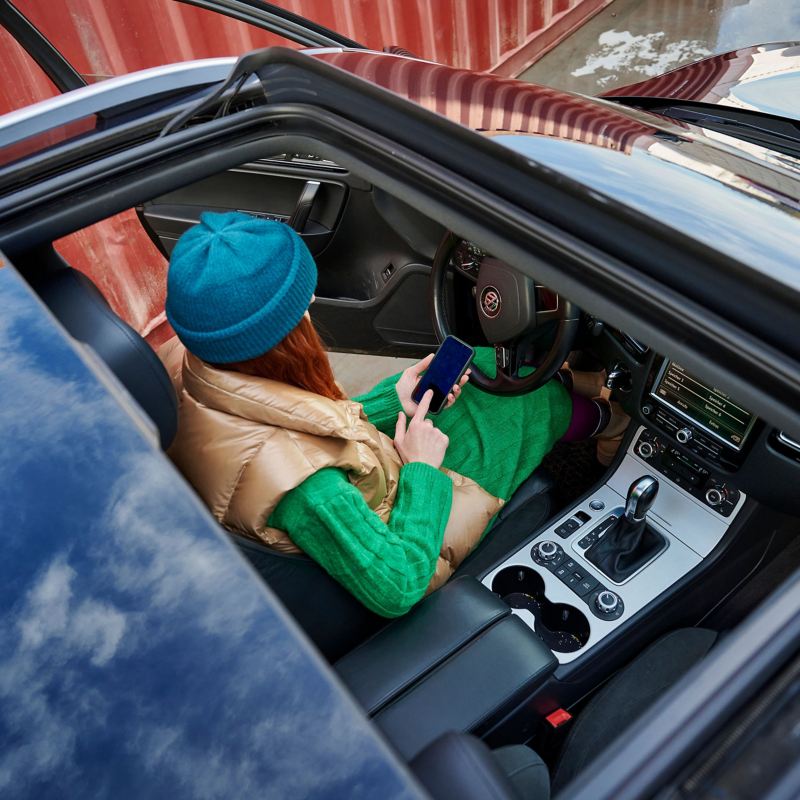 A woman holding a phone in a convertible car