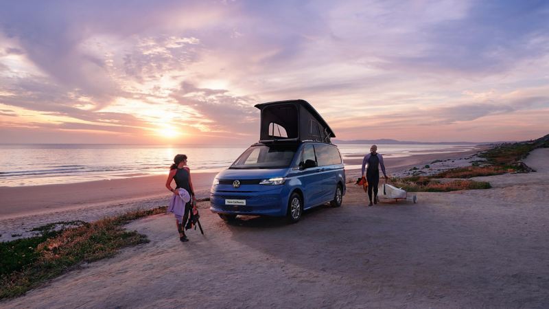 Photo of two VW Californias parked on a beach with their roof units deployed. 