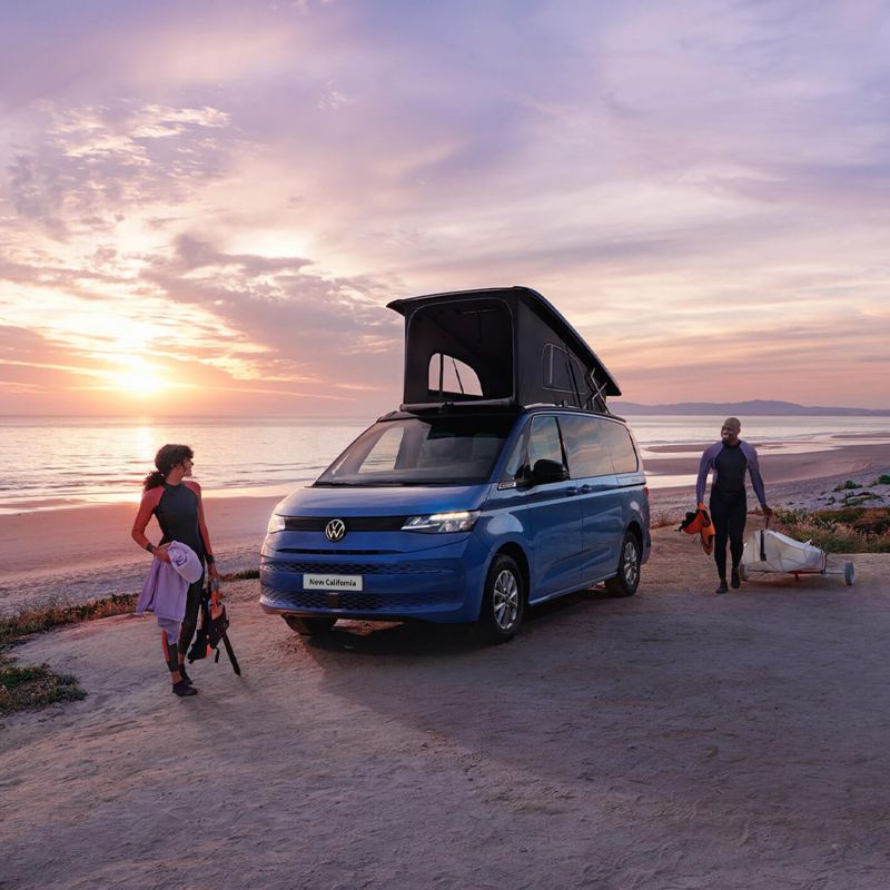 The new California parked on a beach with the roof unit opened and 2 people standing closeby