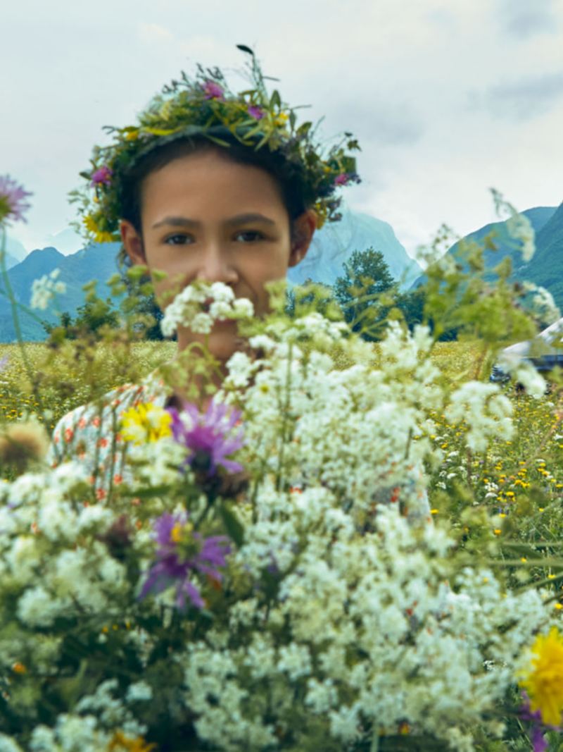 Ein Kind mit einer Blumenkrone in einem Blumenfeld.