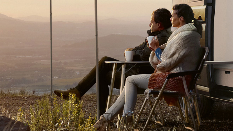 Un uomo e una donna seduti guardano un panorama di montagna mentre bevono un caffè.