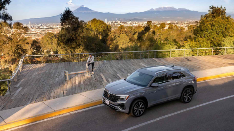 Volkswagen Cross Sport de color gris en un mirador con vista a la ciudad y los volcanes.
