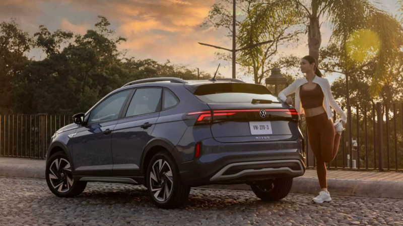 Volkswagen Nivus. Vista trasera de SUV de color azul en calle empedrada junto a mujer estirándose.