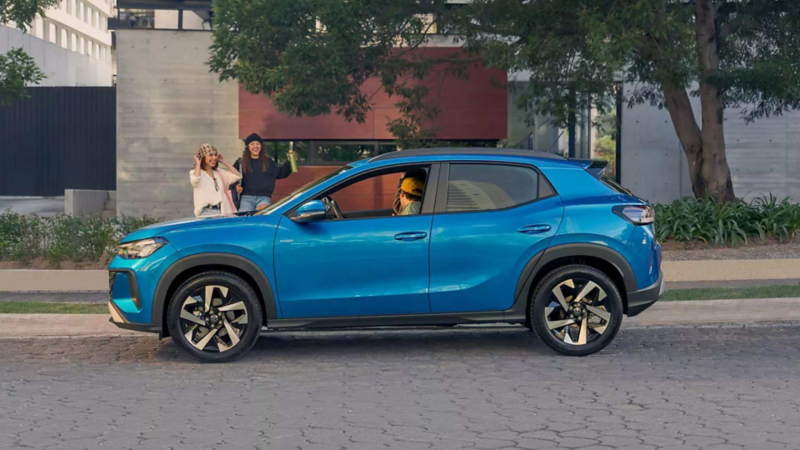 Volkswagen Tera. Vista lateral de SUV de color azul con personas abordo y en exterior en calle arbolada.