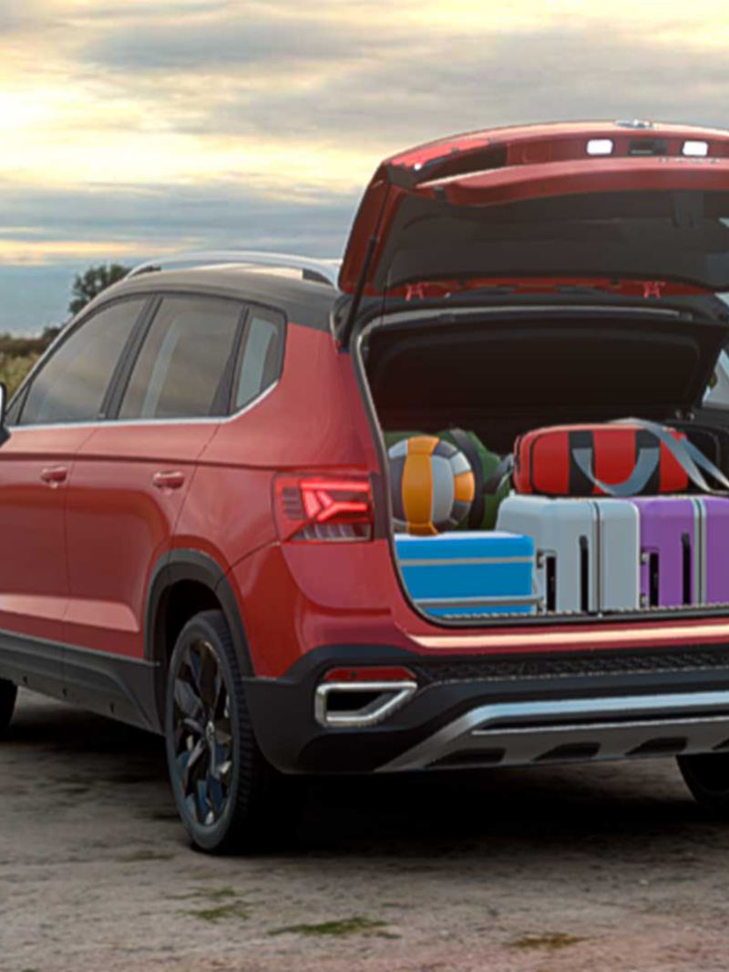 Camioneta 2022 - Taos de Volkswagen en color rojo con cajuela trasera abierta que muestra maletas. 