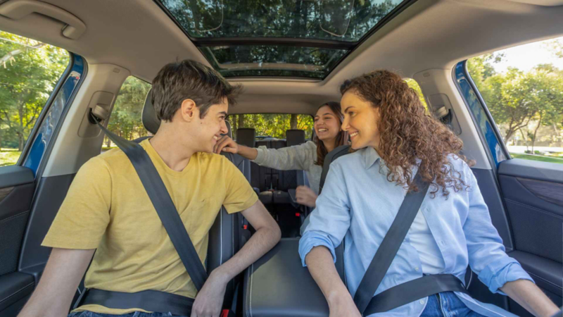 Tres jóvenes sonríen en los asientos de una camioneta Volkswagen Teramont con techo panorámico.