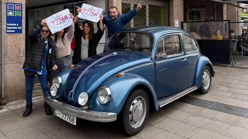 Un grupo ganador de la lotería junto a un Volkswagen Beetle clásico