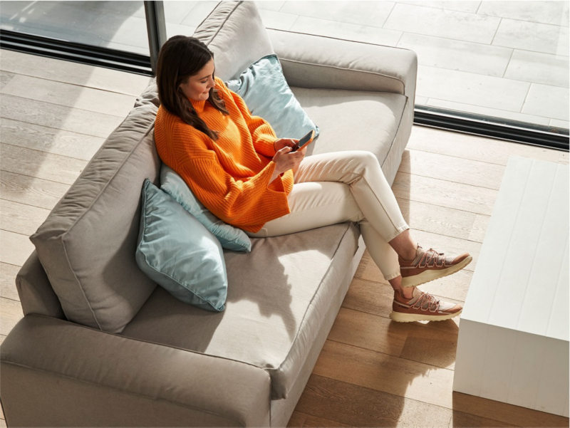 Una mujer sentada en el sofa sosteniendo un smartphone
