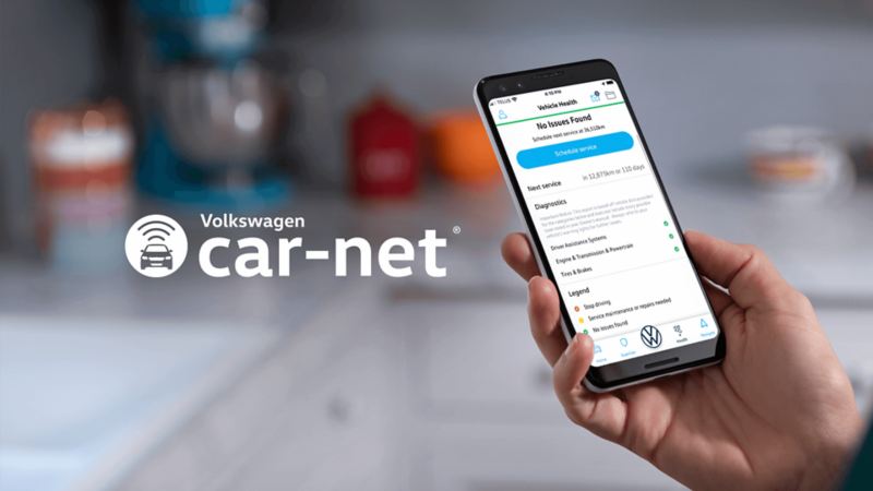 A person holding a phone with the Car-Net® app opened to check vehicle health.