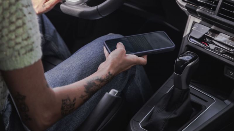 Mujer con celular en la mano en el interior de Volkswagen Polo 2024. 