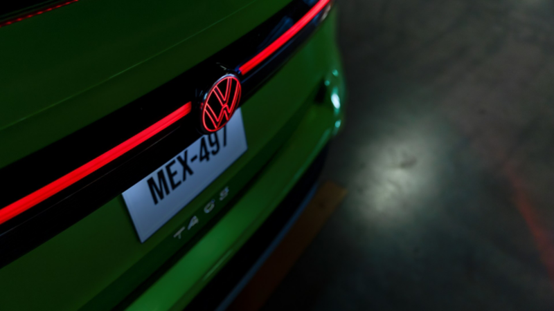 Detalle nocturno de la parte trasera del Taos con luces LED rojas encendidas y emblema VW iluminado en color rojo.