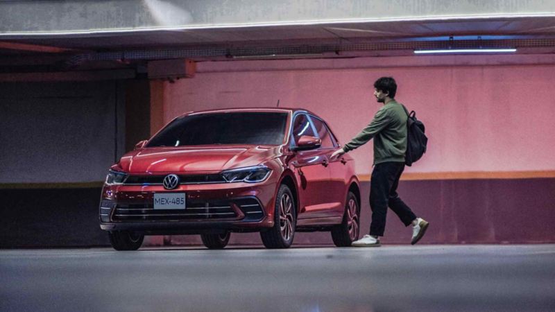 Joven abre puerta de Volkswagen Polo 2024 en color rojo. 