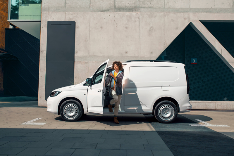 Une femme sort d'un VW Caddy blanc