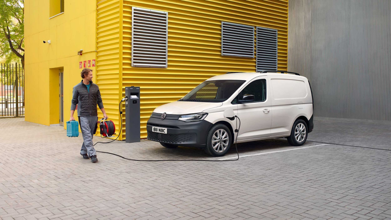 A Caddy Cargo PHEV parked in front of a warehouse. 