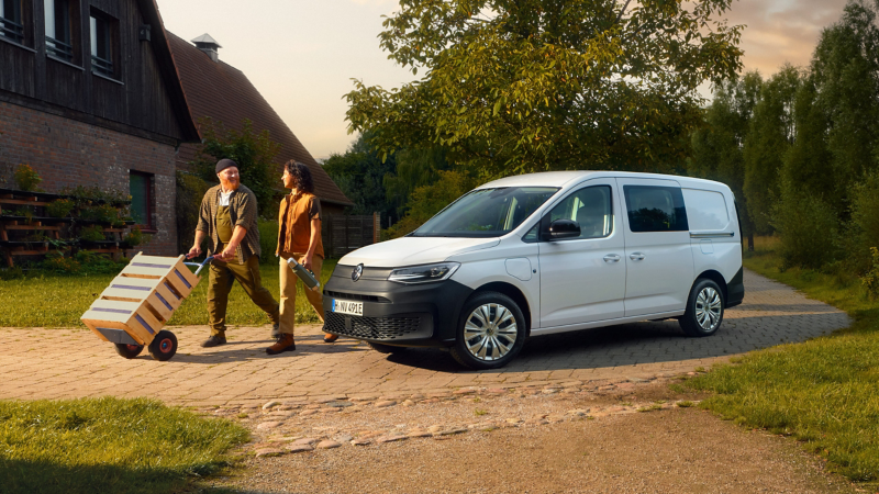 zwei Handwerker die sich von Ihrem geparkten VW Caddy Cargo entfernen.