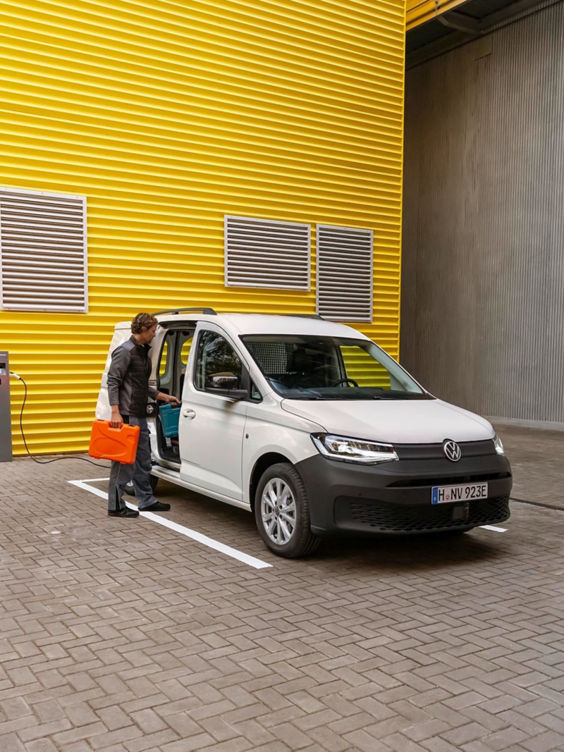 Zwei Handwerker laden ihr Material und Werkzeug aus dem VW Caddy Cargo.