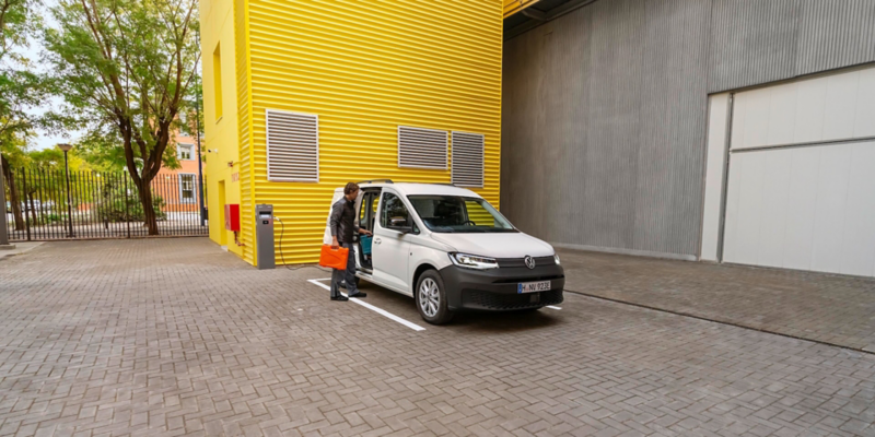Ein Handwerker und eine Handwerkerin holen ihre Werkzeuge aus einem VW Caddy Cargo.