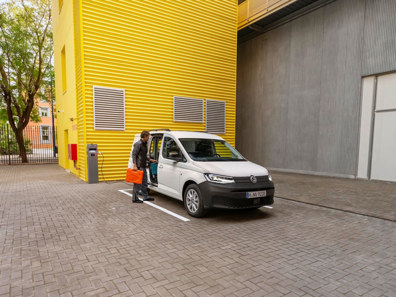 Zwei Handwerker laden ihr Material und Werkzeug aus dem VW Caddy Cargo.