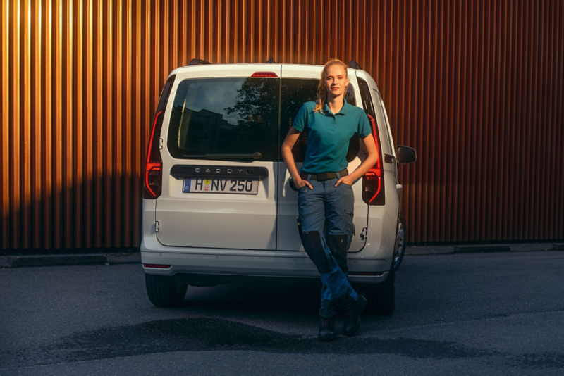 Caddy cargo blanc et une personne posée sur le coffre