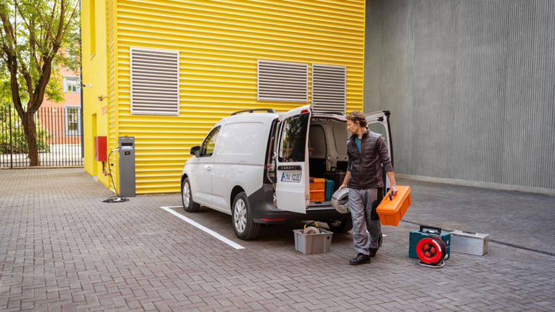 En kvinna står bakom en VW Caddy Cargo