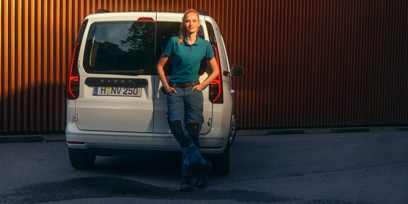 En kvinna står bakom en VW Caddy Cargo