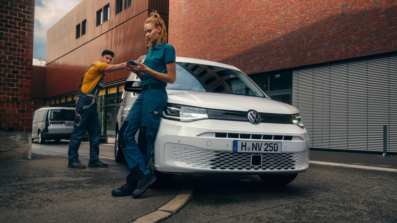 Zwei Handwerker lehnen sich an einen VW Caddy Cargo.
