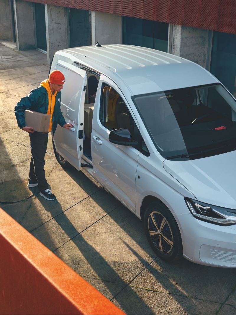 Ein Kurier öffnet die Seitentür eines VW Caddy Cargo.