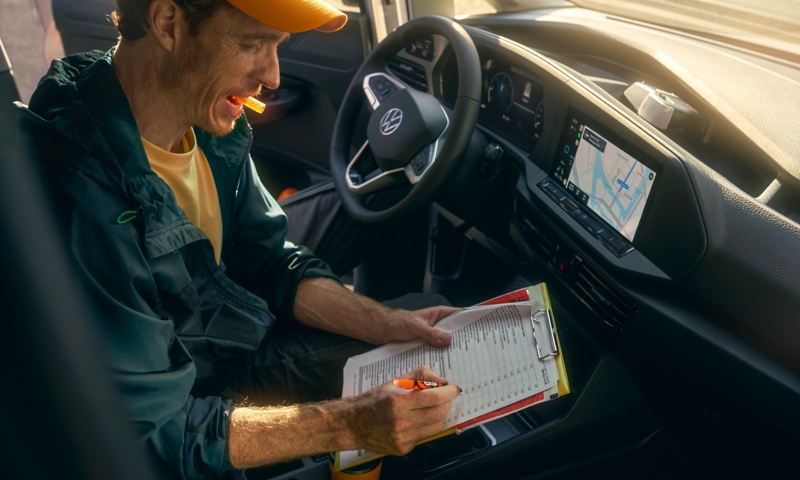 A tradesman with clipboard in the VW Caddy Cargo.