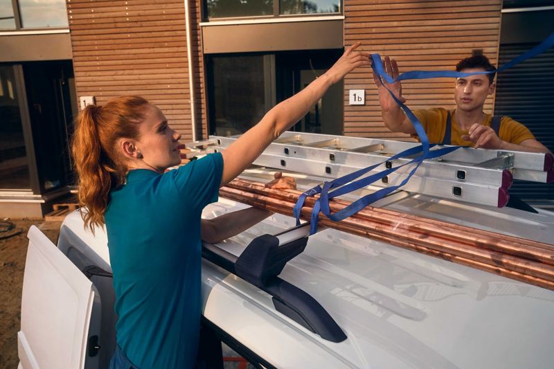 Kobieta i mężczyzna mocujący drabinkę na dach nowego Volkswagena Caddy Cargo