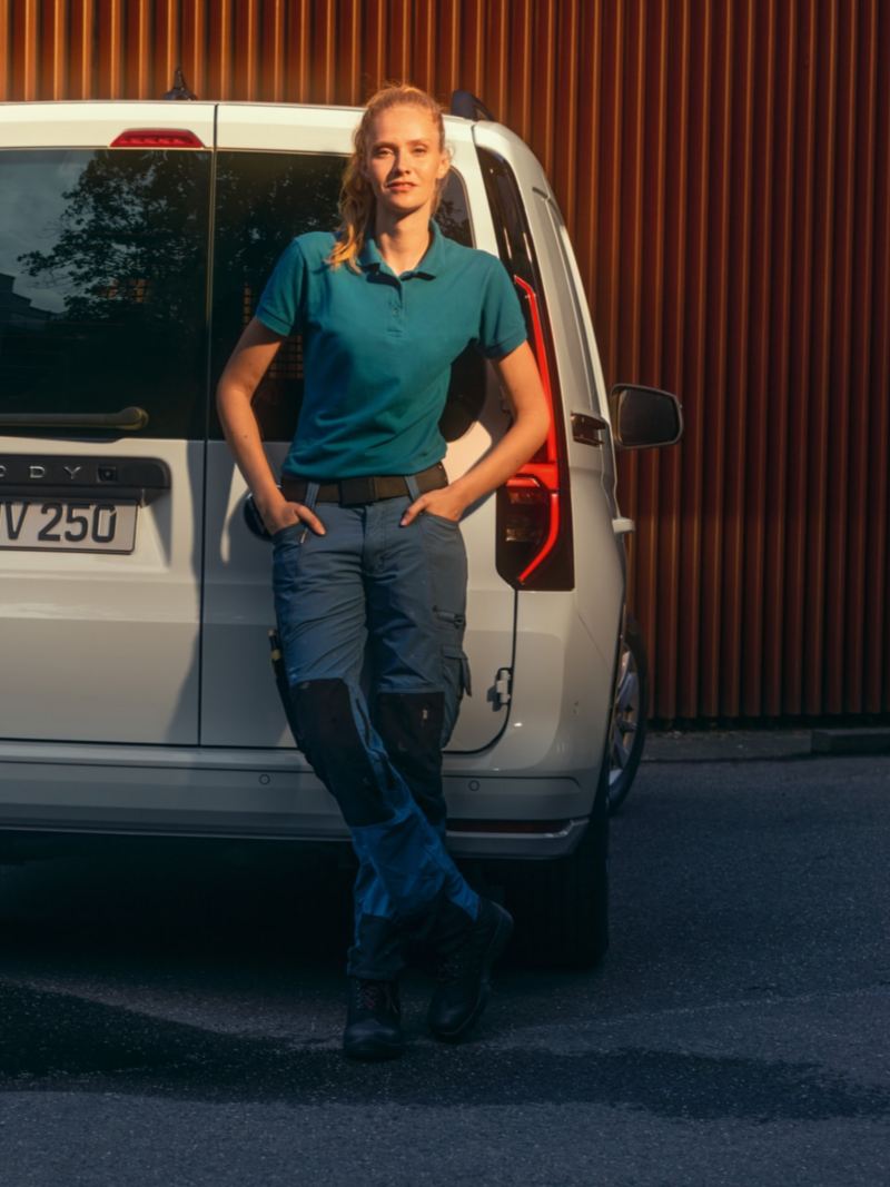 Une femme s’appuie aux portes battantes arrière du nouveau Volkswagen Caddy Cargo. 