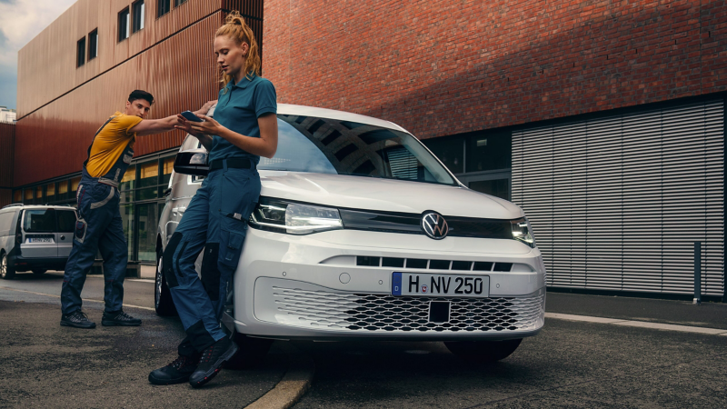 Zwei Handwerker lehnen sich an einen VW Caddy Cargo.