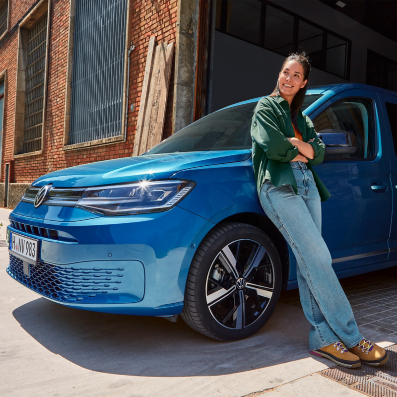 En person lutar sig mot en blå VW Caddy.