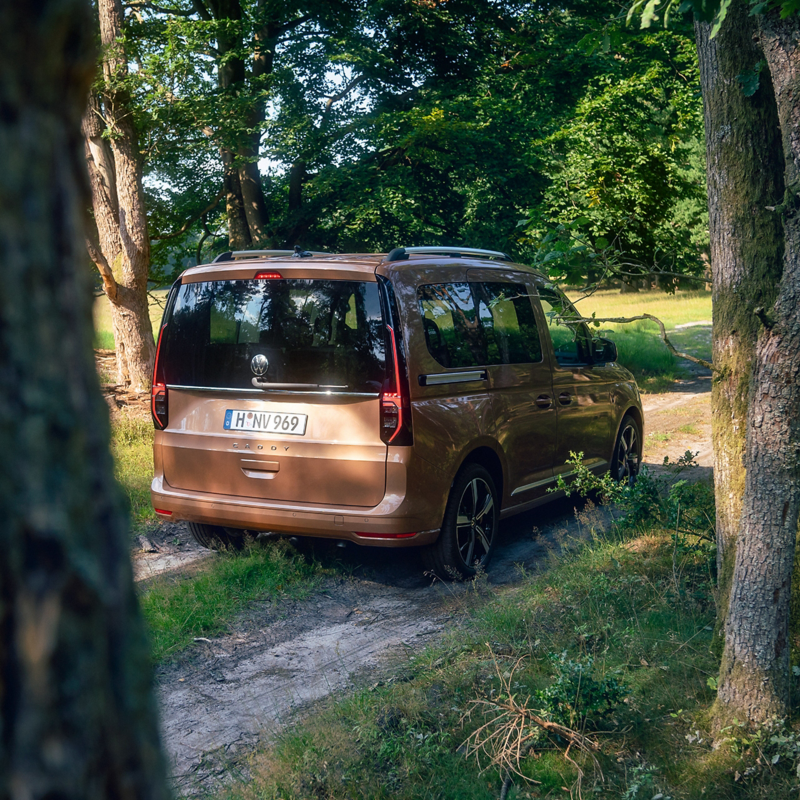 En VW Caddy på en grusväg i skogen.